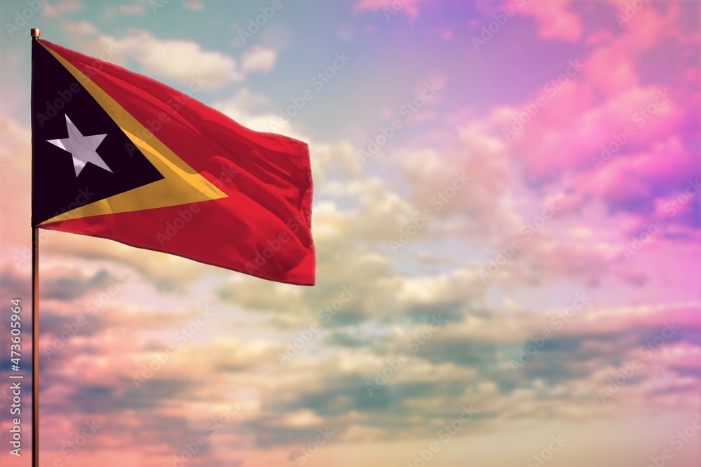 Fluttering Timor-Leste flag mockup with the space for your content on colorful cloudy sky background. Fluttering Timor-Leste flag mockup with the space for your content on colorful cloudy sky background.