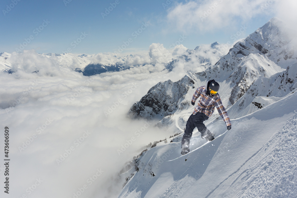 A jumping snowboarder in the mountains. Snowboarding, winter extreme sport.