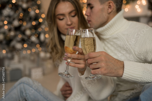 We celebrate Christmas and New Year. Couple holding glasses of champagne, glasses of champagne close-up in the hands of a man and a woman.