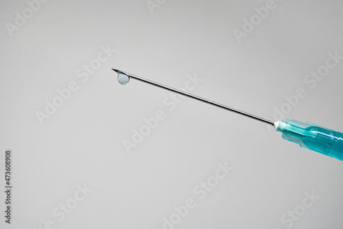 Needle of a syringe with a drop of the drug on the tip on a white background