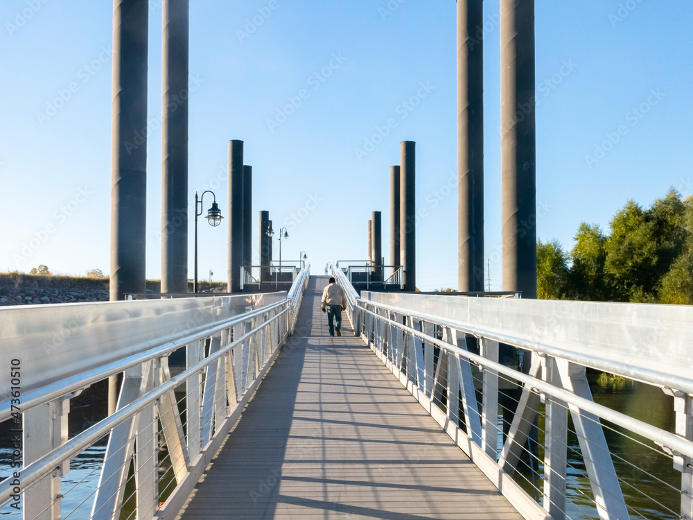A man walking up a large ramp from a pier with large pilings.