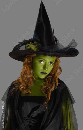 Portrait of a woman dressed as a witch with green body paint, looking into camera with attitude