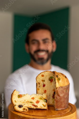 delicious Christmas panettone cut into slices, man holding, smiling in the background.