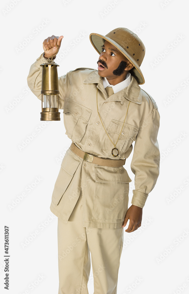 Portrait of a boy dressed up as archaeologist mummy hunter with a fake mustache and sideburns holding a lantern, against a white background Portrait of a boy dressed up as archaeologist mummy hunter with a fake mustache and sideburns holding a lantern, against a white background