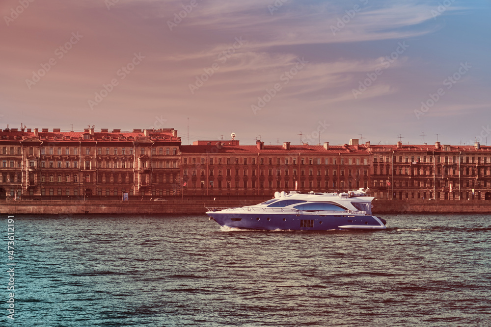 Obraz premium The yacht is sailing on the river in the city . Beautiful boat on the background of architecture . Travel by water .
