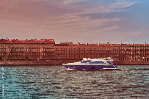 The yacht is sailing on the river in the city . Beautiful boat on the background of architecture . Travel by water .