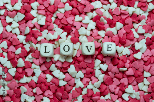 Wooden cubes with the words LOVE on a heart shape candy background. Valentine s Day concept