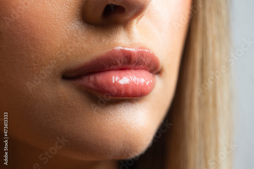 Close up of a young Hispanic woman's lip with glossy lipstick. photo
