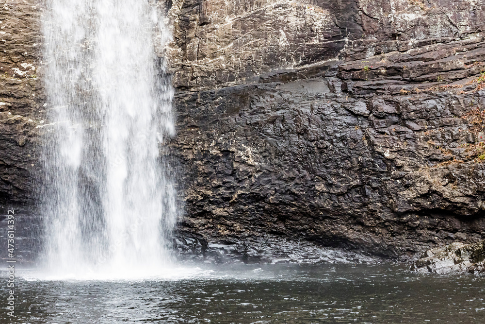 A waterfall against a cliff falling into a pond. A waterfall against a cliff falling into a pond.