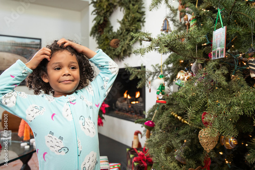 Young girl having fun while decorating Christmas tree in living room. photo