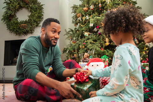 Portrait of a happy African American father and daughter opening Christmas gifts together and smiling. photo