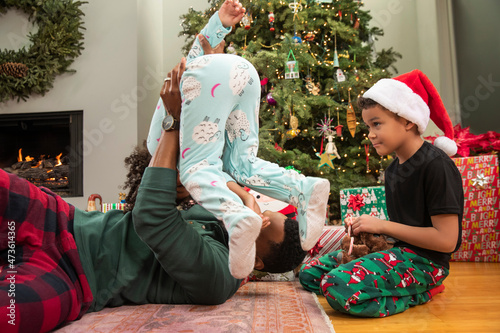 Happy African American family playing around on floor by Christmas tree. photo