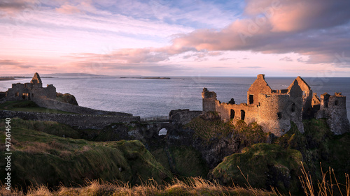 Expansive Dunluce Castle. The iconic ruins of Dunluce Castle perched on a rocky outcrop on the North Antrim Coast in Northern Ireland.