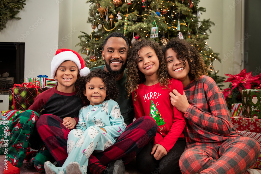 Loving family sitting under Christmas tree posing. Loving family sitting under Christmas tree posing.