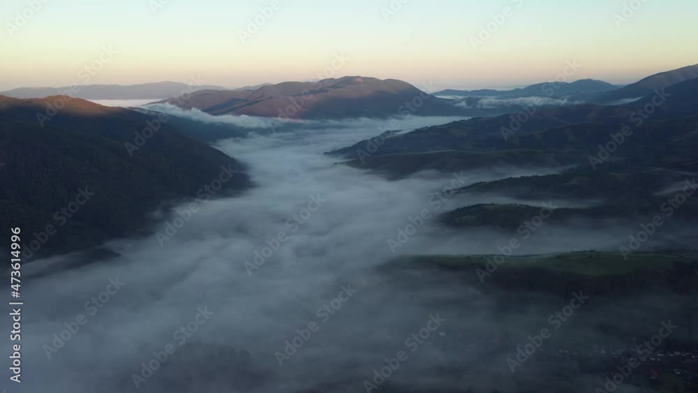 Aerial view on amazing flowing morning fog spreads over green meadows in autumn mountains. Ukrainian Carpathian mountains. UHD 4k video