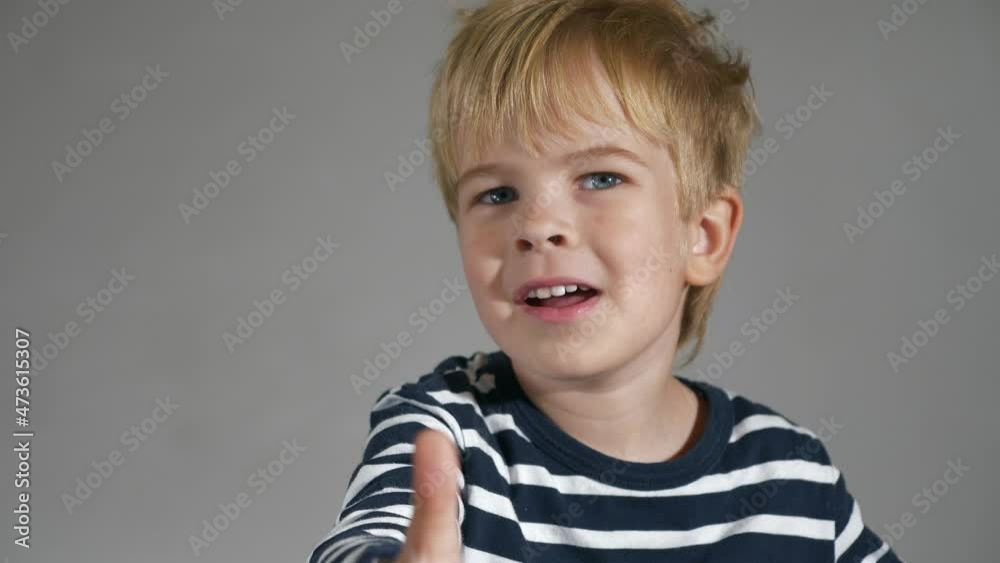 Child Shows Thumbs Up Gesture. Portrait Cute Little Boy. Happy Facial Expression Emotion Glad Smiling Face. Kid against White Wall Background. 2x Slow motion 4K
