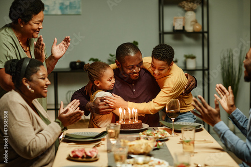 Portrait of smiling African-American man embracing children while celebrating Birthday with big happy family photo