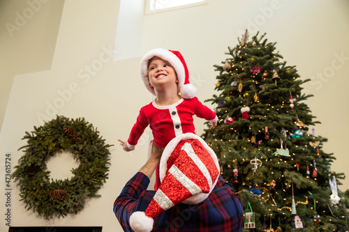 Family playing in front of Christmas tree as father lifts son up over his head. photo