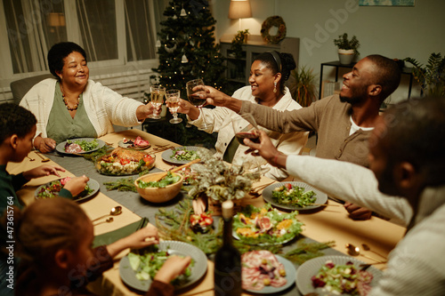 High angle view at happy African-American family toasting with glasses while enjoying dinner together at Christmas