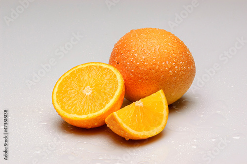 Oranges cut in half with water droplets isolated on white background.