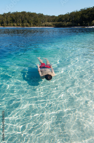 Boy swimming underwater in clear water of Lake McKenzie - Fraser Island photo