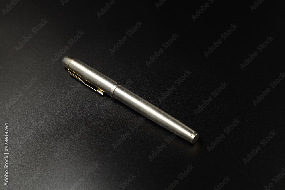 Metal pen on black background