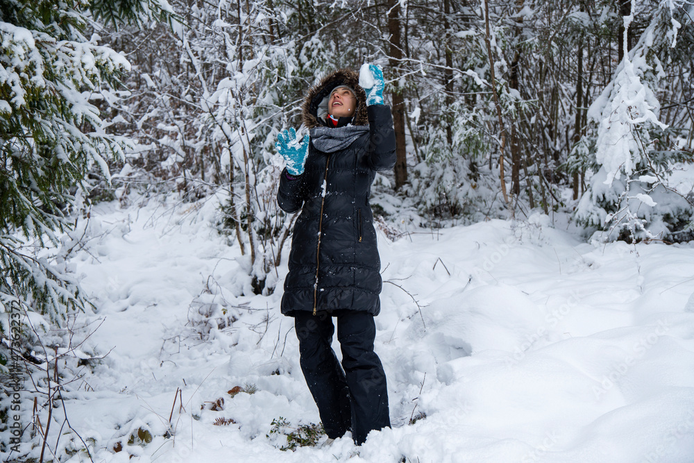 Caucasian woman in winter forest. Girl enjoys the snow falls. Have a good time outdoor in a snowy forest. Attractive young woman in wintertime outdoor.