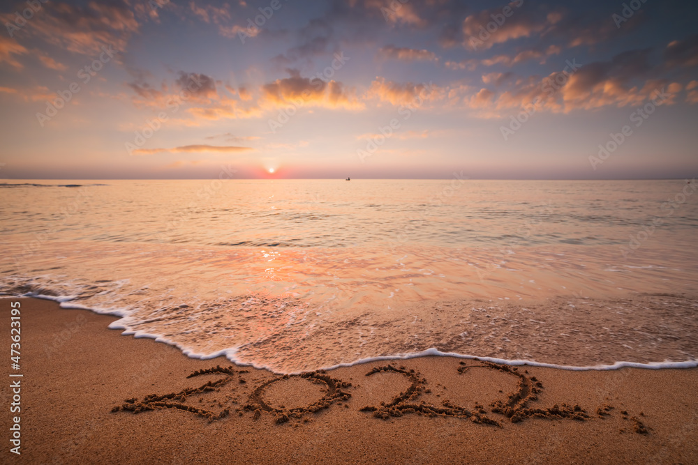 Sea sunrise over the beach. New year 2022 text on the sand.