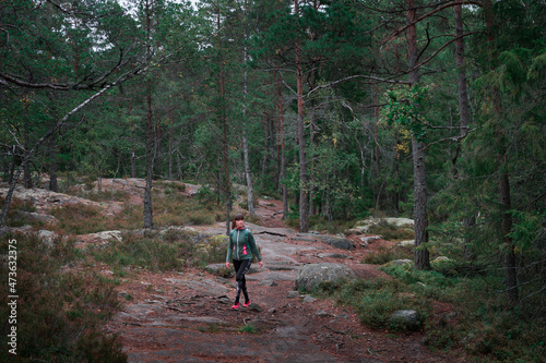 Woman hiking through green forest in Tyresta National Park in Sweden.