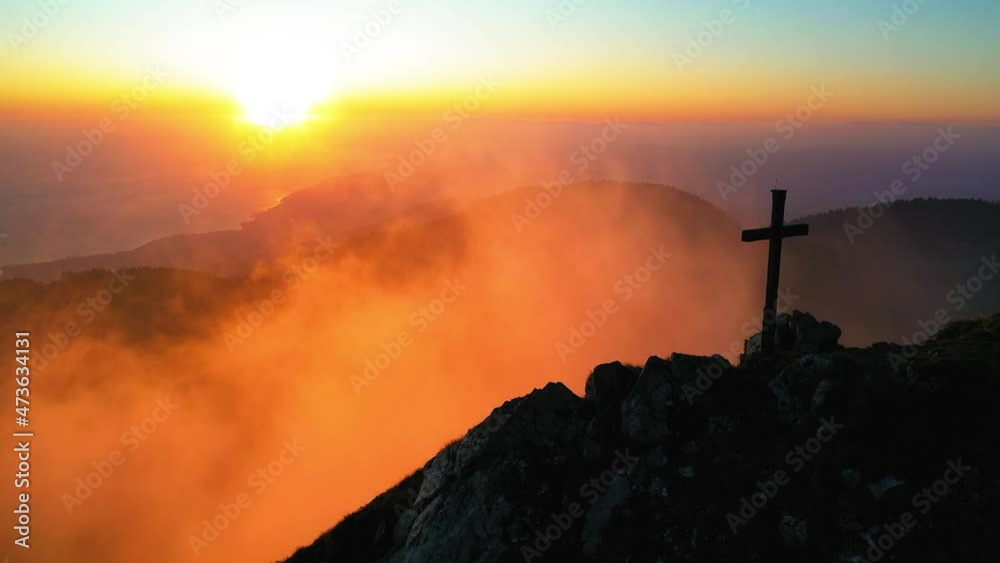 Aerial Panning Cross Symbol On Mountain Top, Drone Flying Backwards Over Orange Clouds During Sunset - Cape au Moine, Switzerland