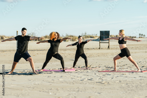 Yoga teacher conducting a class with multiethnic people on a beach