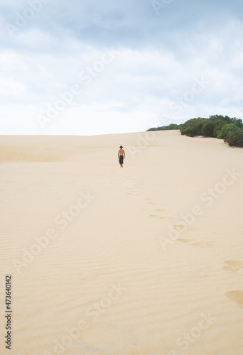 Vertical Image.Rear View of Young Man Walking on a Sand Dune in a Sunny Day.Exploration Concept.