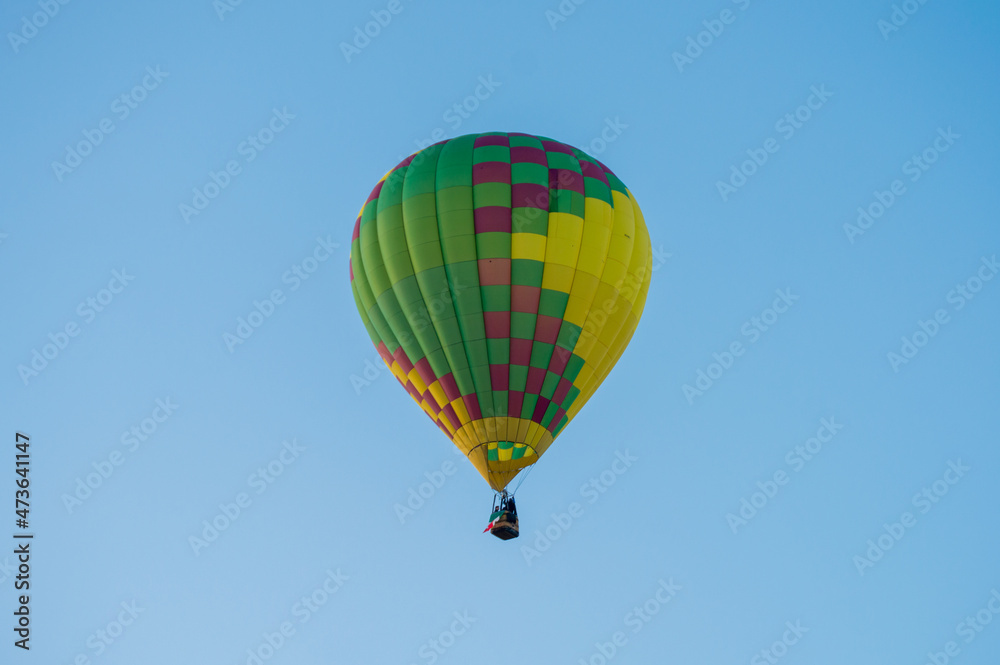 Naklejka premium Globo aerostático de colores volando sobre el cielo azul 