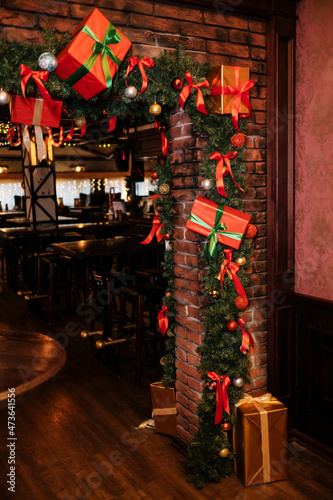 Christmas tree with cones and toys. Christmas gifts with bows. Pub entrance decoration.