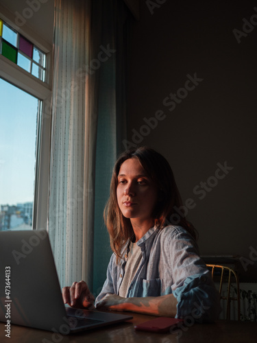 Woman working on laptop at home in the evening
