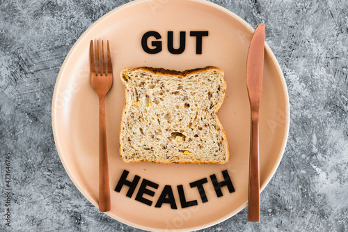 gut health text with wholegrain multiseeds slice of bread on dining plate with fork and knife, healthy nutrition research about the microbiome photo