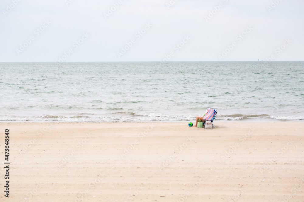 Two people sitting on a beach with heads covered Two people sitting on a beach with heads covered