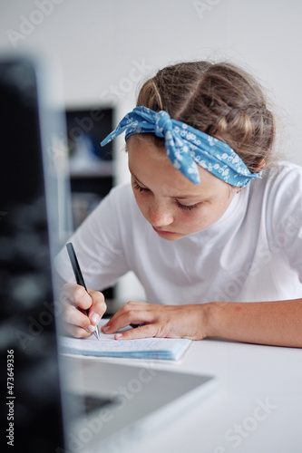 Girl try to comply her own homework independently photo