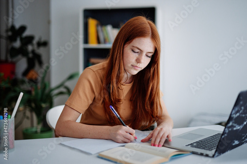 Beautiful student using books for writing text