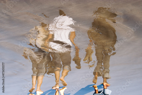 Reflection of 3 people on the shore of the beach photo