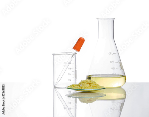 Closeup chemical ingredient on white laboratory table. Sodium sulfide flake in Chemical Watch Glass place next to Aluminium chloride liquid in Erlenmeyer flask. Side View photo