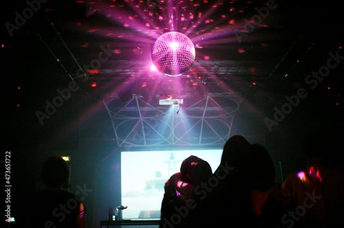 Anonymous people dancing and a purple mirrorball photo