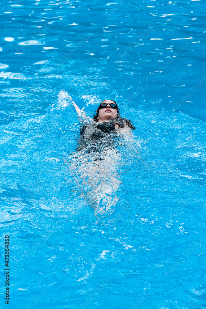 Aquatic woman swimming backwards at pool Aquatic woman swimming backwards at pool