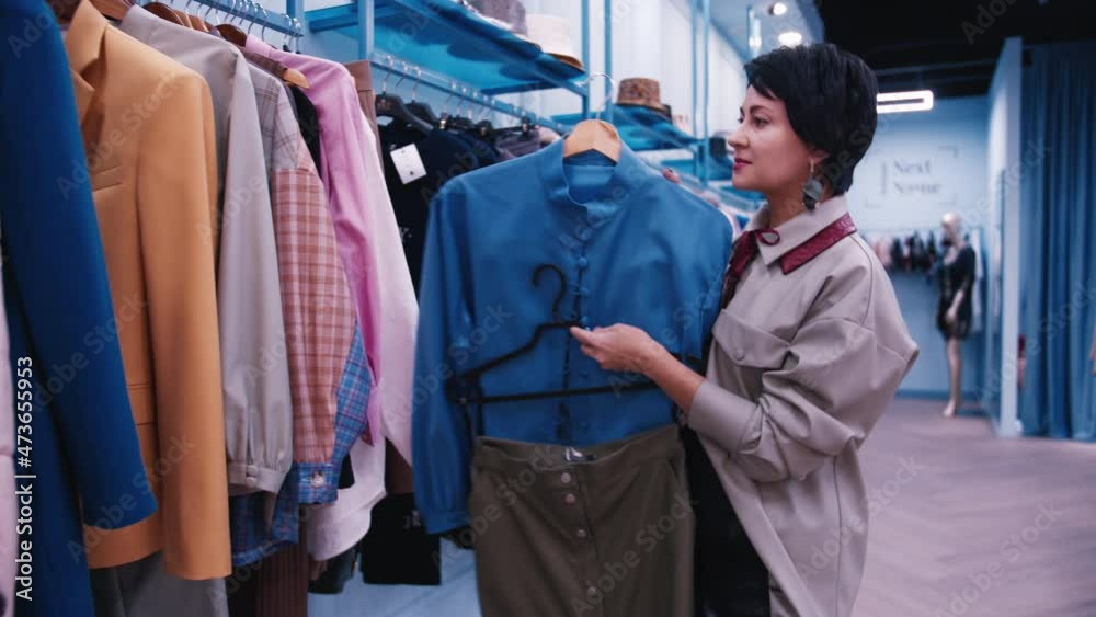 designer in the store gives advice on choosing clothes, woman shopping in a clothing store, chooses clothes carefully designer in the store gives advice on choosing clothes, woman shopping in a clothing store, chooses clothes carefully
