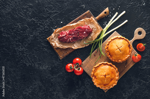 Tasty beef pot pies with meat on dark background