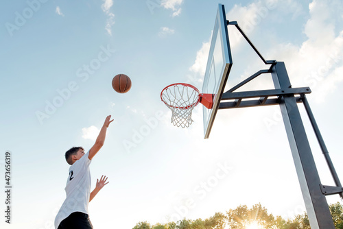 Teen boy playing basketball on a beautiful day.  photo