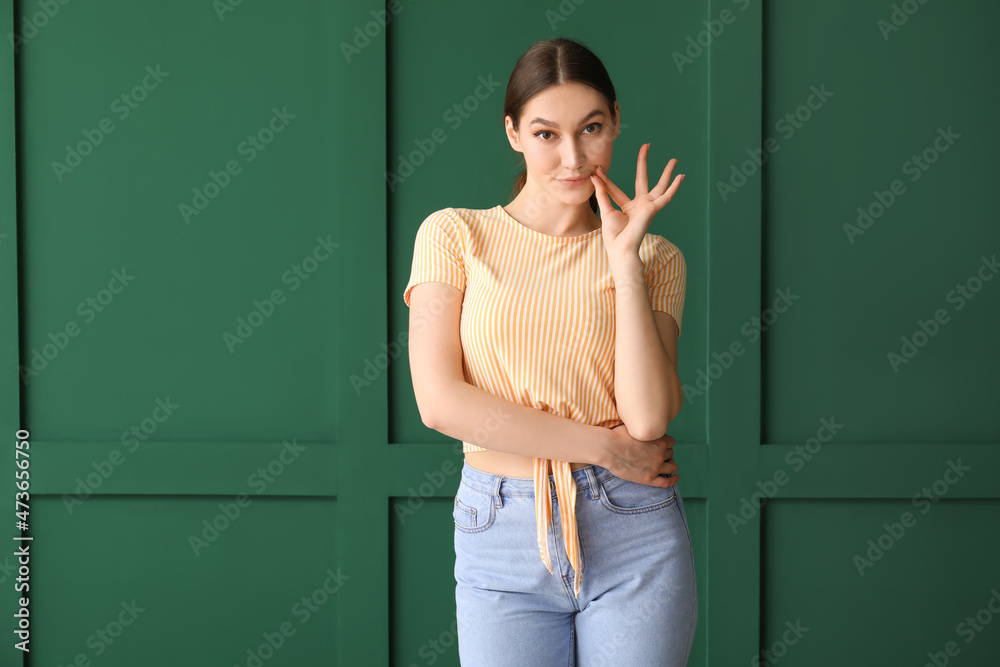 Young woman zipping her mouth on color background