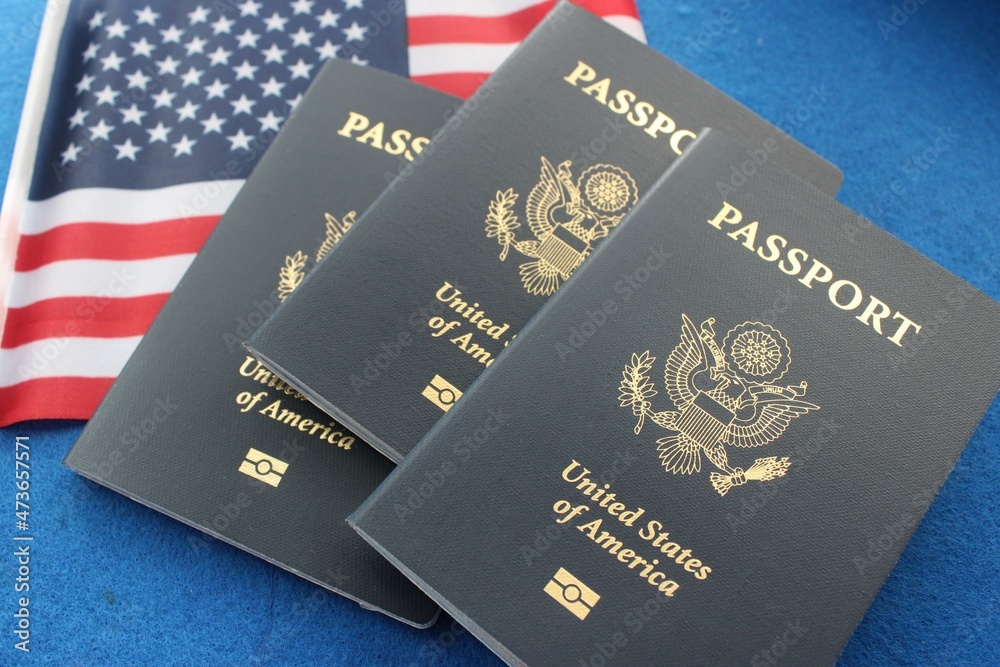 Three US passports with American flag, on blue background Three US passports with American flag, on blue background