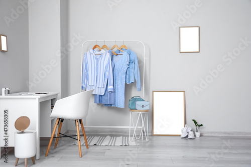 Interior of light room with modern workplace, clothes and blank frames © Pixel-Shot