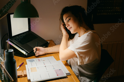 Female student doing homework on her desk photo